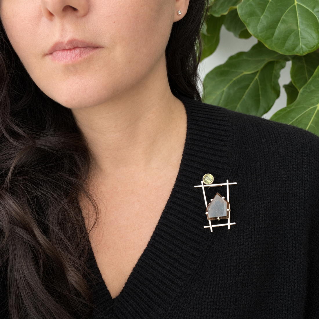 Modern geometric silver brooch with architectural lines, raw gemstone settings, and a minimal aesthetic worn as a statement accessory on a professional black wardrobe.