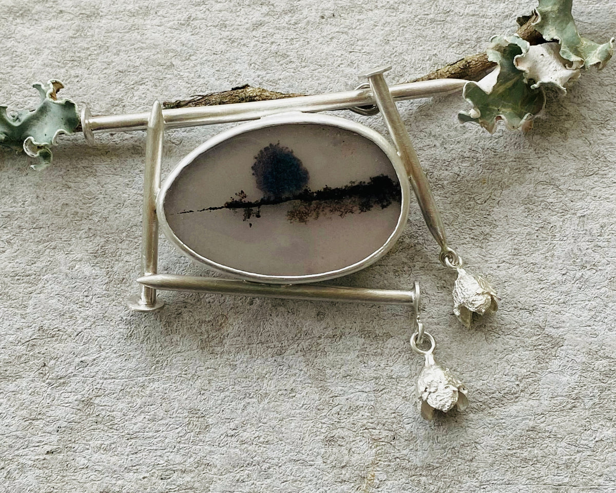 Architectural sterling silver brooch with an oval scenic dendritic agate slice set within a brutalist linear frame comprised of hand handfabricated nails, representing the brooches collection.