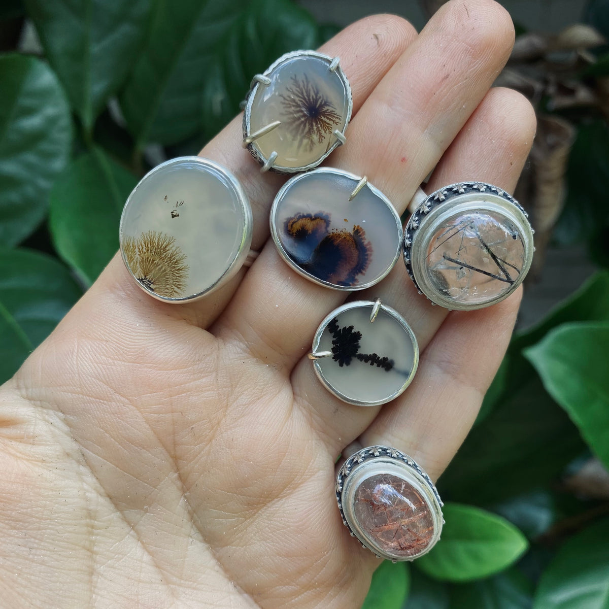 Six handcrafted sterling silver rings featuring dendritic agate and rutilated quartz stones unique natural inclusions, representing the rings collection.